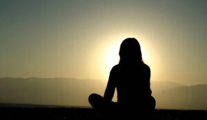 vrouw zit in meditatiehouding om zelfcompassie te beoefenen